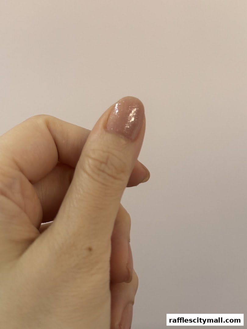 A hand with a beautifully manicured nail showing a subtle glitter finish.