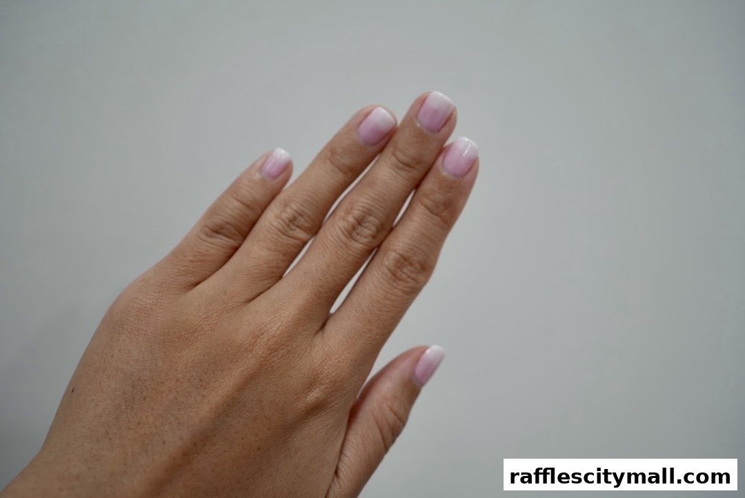 A close-up shot of a hand with perfectly manicured French tip nails against a plain background.