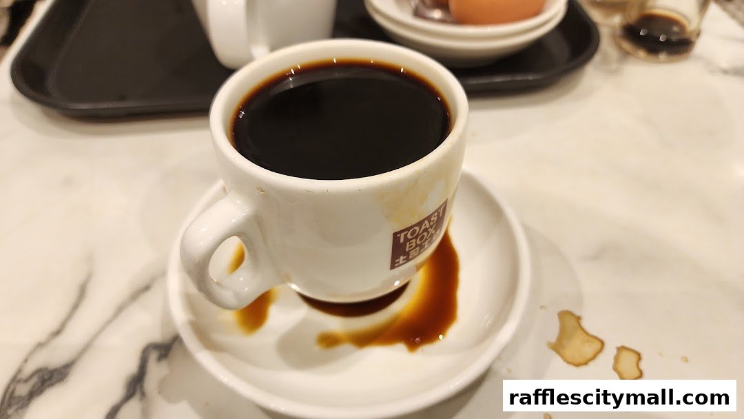 A close-up of a cup of black coffee with the Toast Box logo on the saucer.