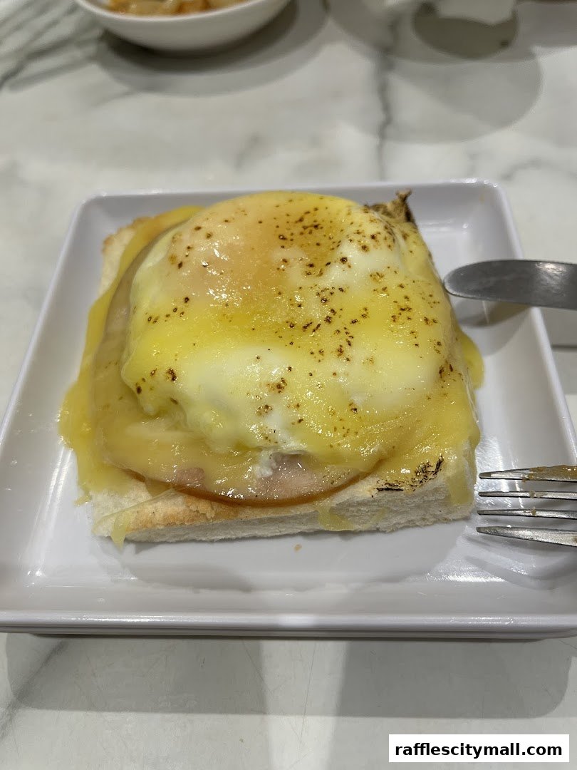 A close-up of a delicious breakfast dish with toast, ham, and a perfectly cooked egg.