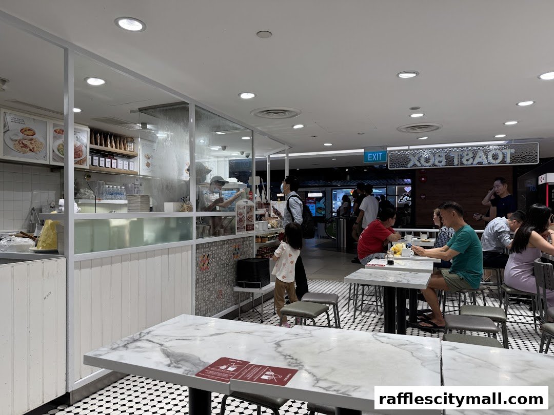 Interior view of Toast Box Raffles City with customers dining and staff preparing food.