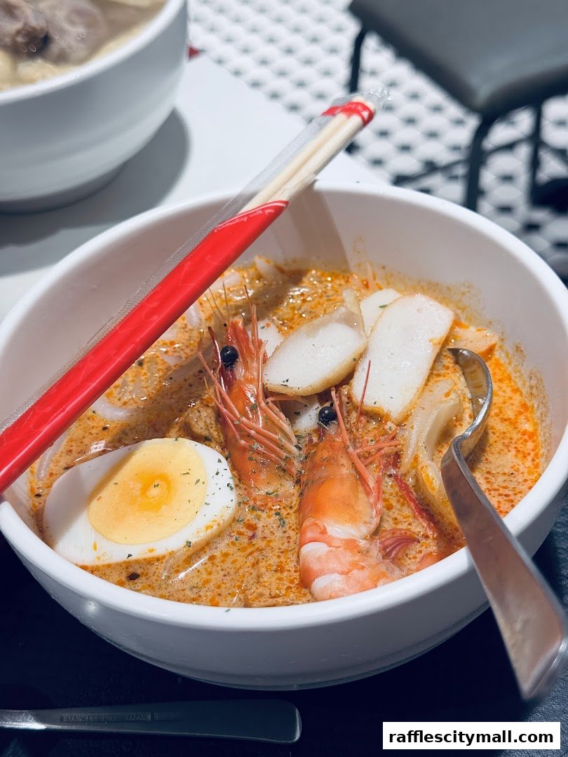 A close-up shot of a delicious bowl of Laksa with prawns, egg, and fish cakes.