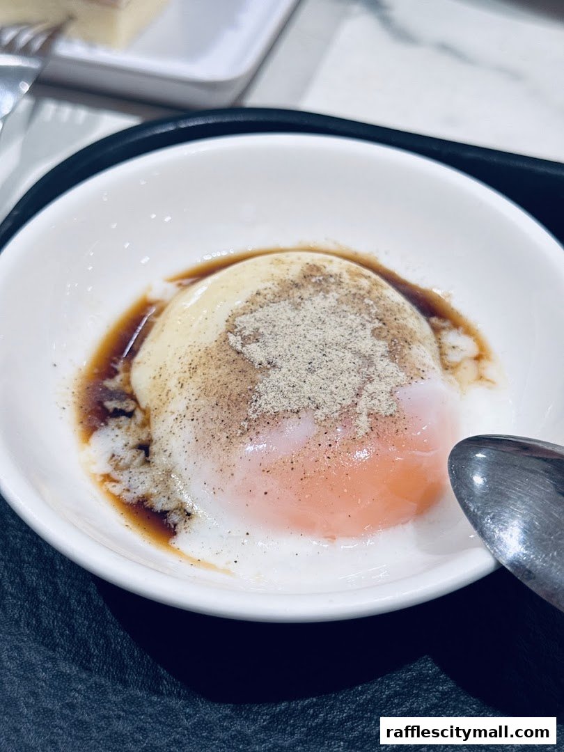 A close-up of a soft-boiled egg with soy sauce and pepper in a white bowl.