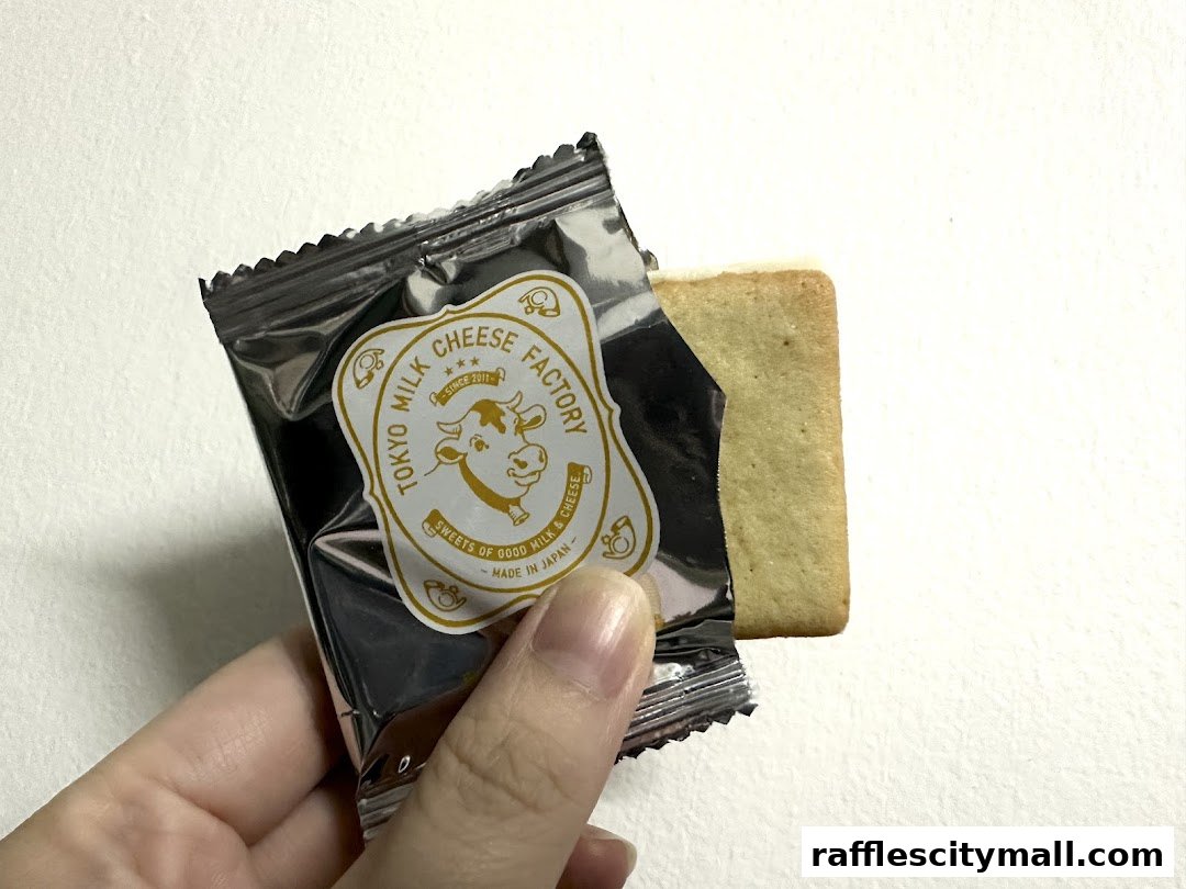 A hand holds a foil-wrapped cookie from Tokyo Milk Cheese Factory.