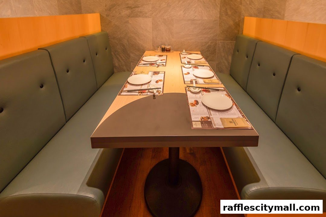 A dining table set for four with placemats, plates, and chopsticks in a restaurant booth.