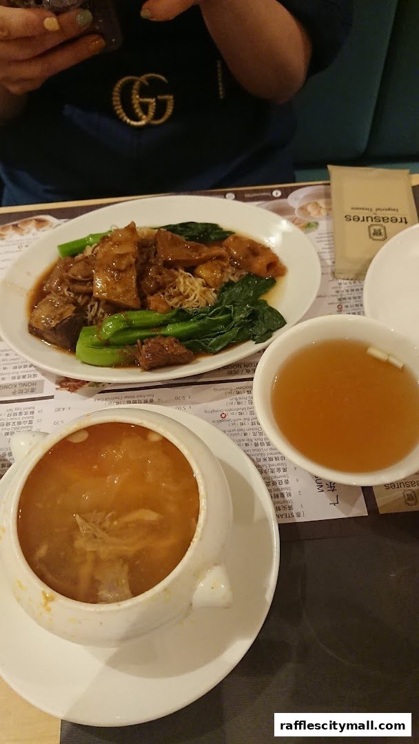 A table setting with two bowls of soup and a plate of noodles with meat and vegetables.