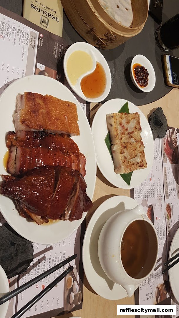A table laden with various Chinese dishes, including roasted meats and dim sum.