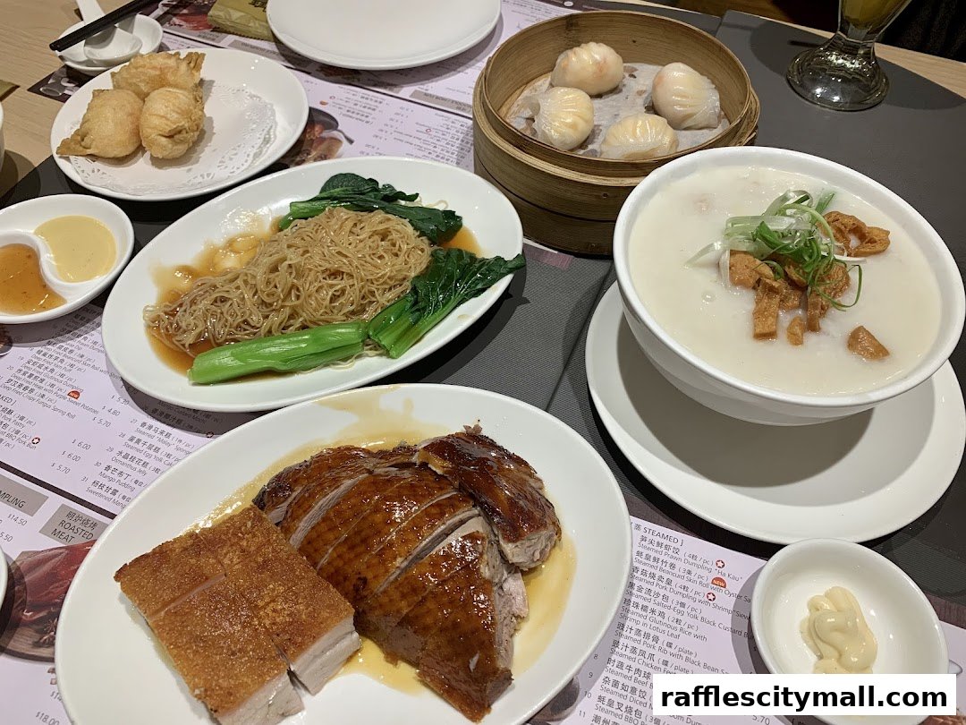 A table laden with various Chinese dishes including roasted duck, crispy pork, noodles, dim sum, and congee.