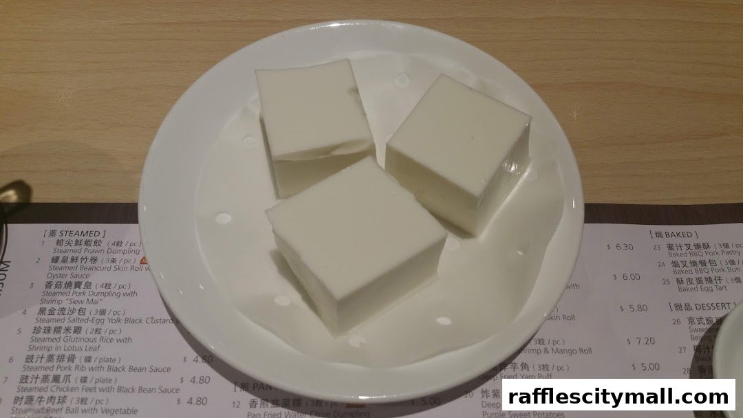 A white plate holds three white, cubed desserts, likely a sweet treat.