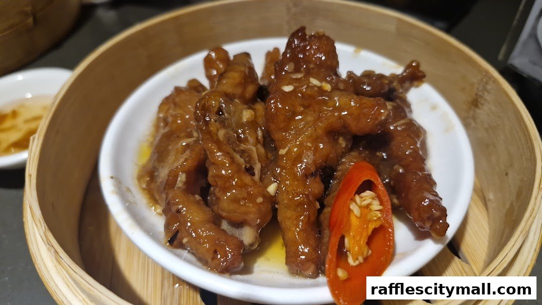 A close-up of braised chicken feet in a bamboo steamer, garnished with chili.