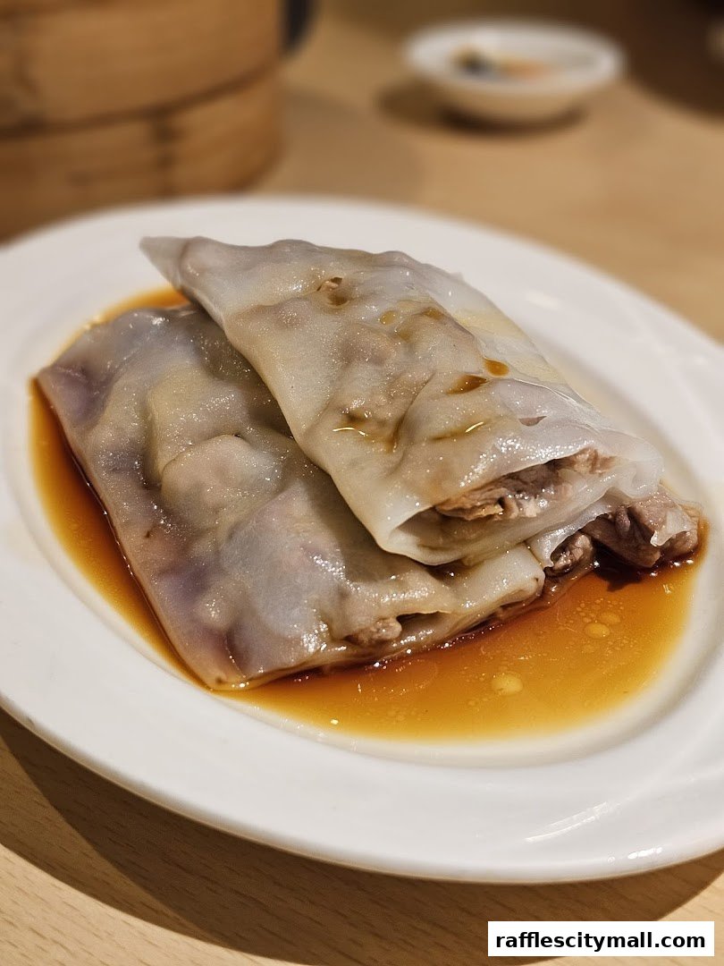 A close-up shot of two delicious steamed rice noodle rolls with savory filling.