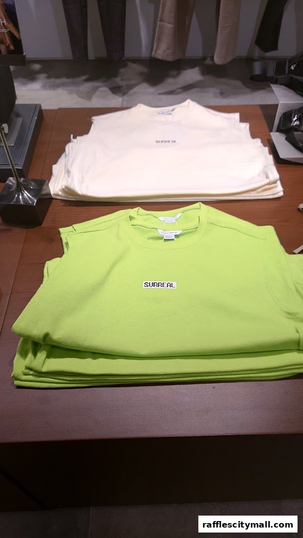 Neatly folded t-shirts in cream and lime green with 'SURREAL' branding displayed.