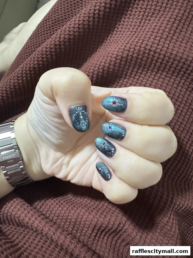 A hand with intricately designed nails, featuring a celestial theme with stars and moons.