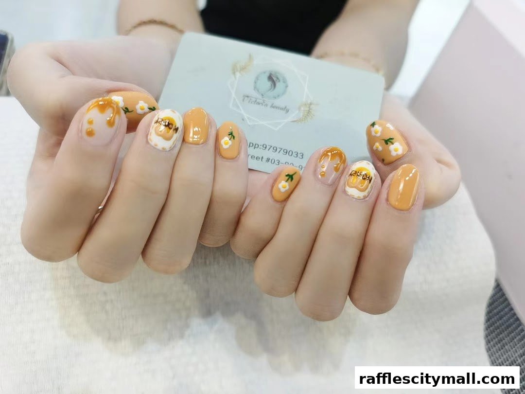 A person displays beautifully designed nails with a yellow and white theme, featuring floral and drip art.