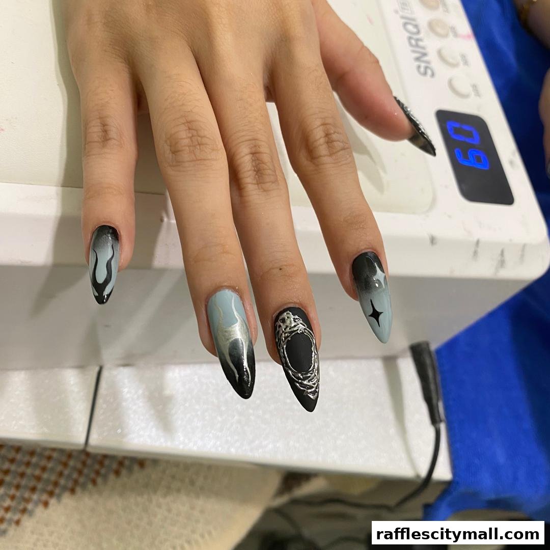 A close-up of a hand with intricately designed black and light blue nails.