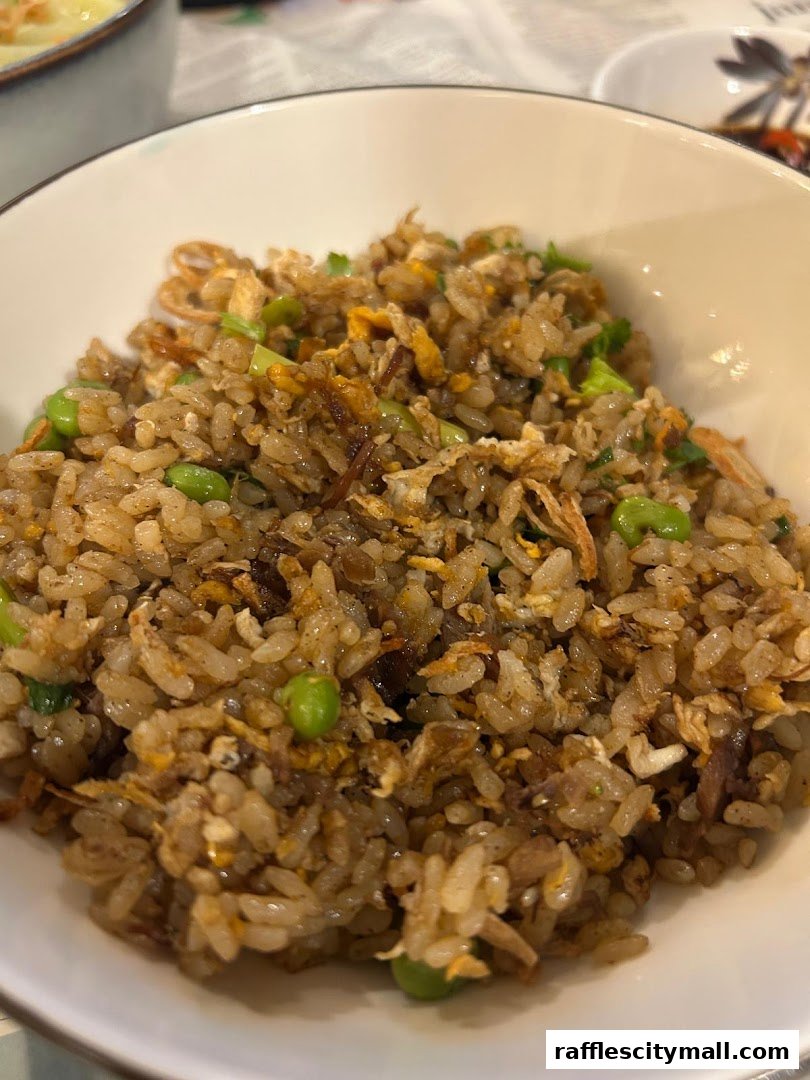 A close-up shot of a bowl of savory fried rice with peas and other ingredients.
