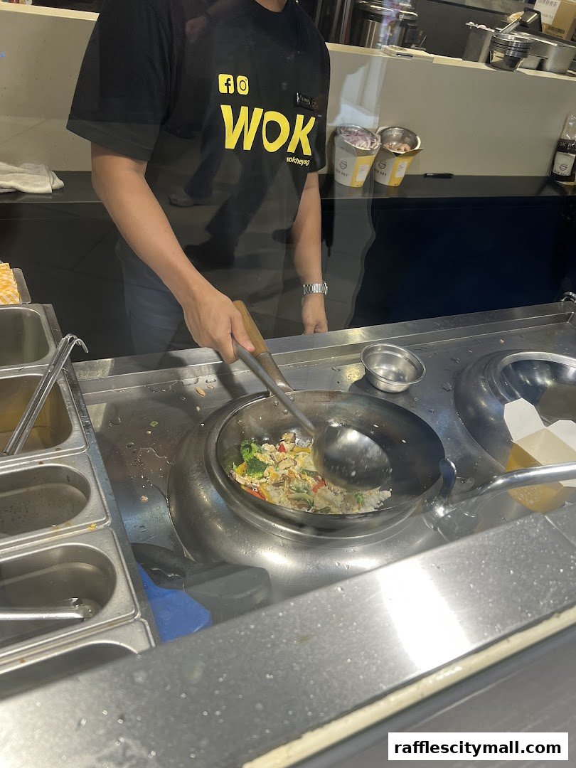 A chef is stir-frying rice with vegetables in a wok at WOK HEY.