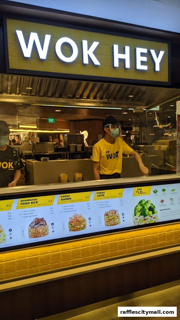 A Wok Hey counter with staff and a display of menu items and prices.