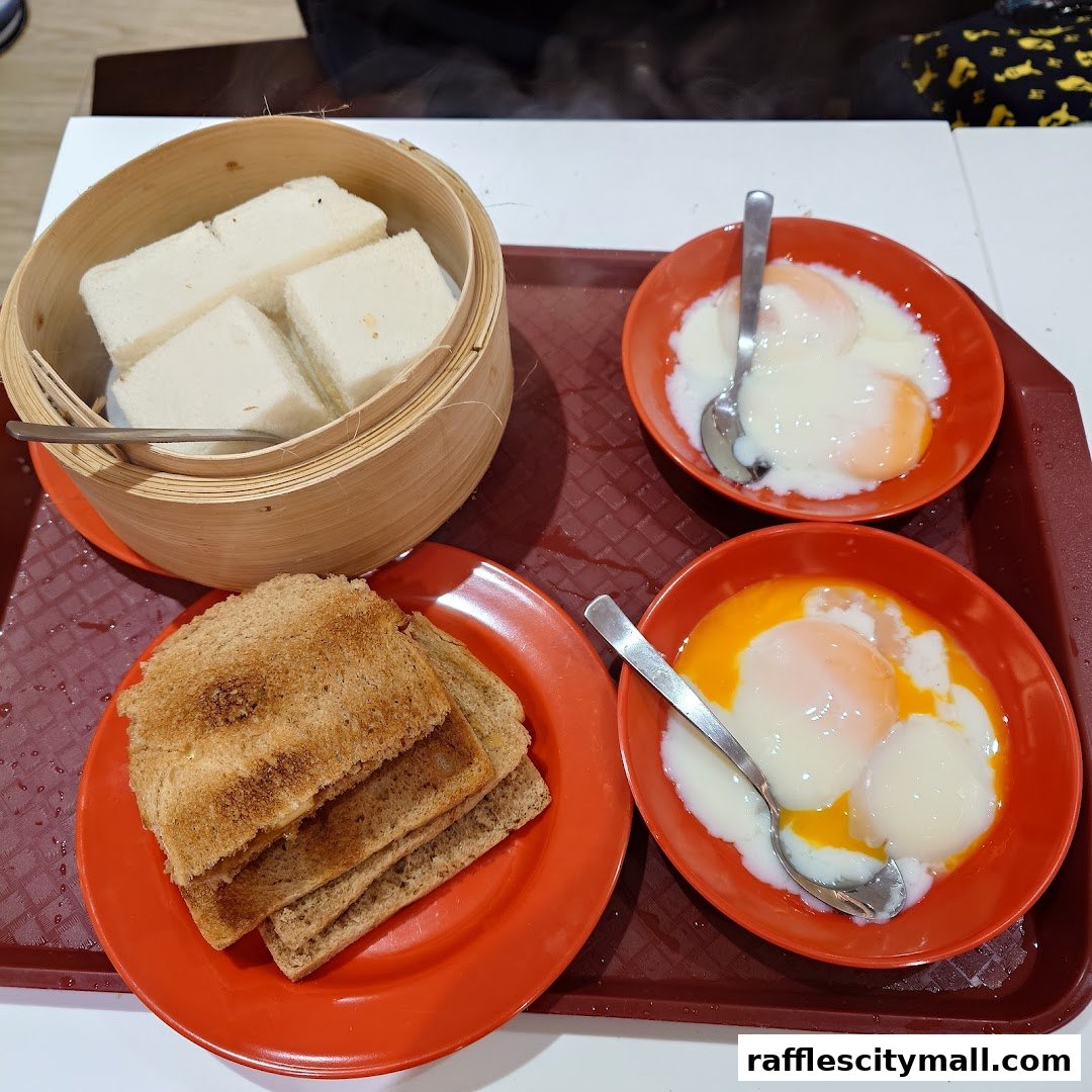 A tray of traditional Singaporean breakfast items including kaya toast, steamed bread, and soft-boiled eggs.