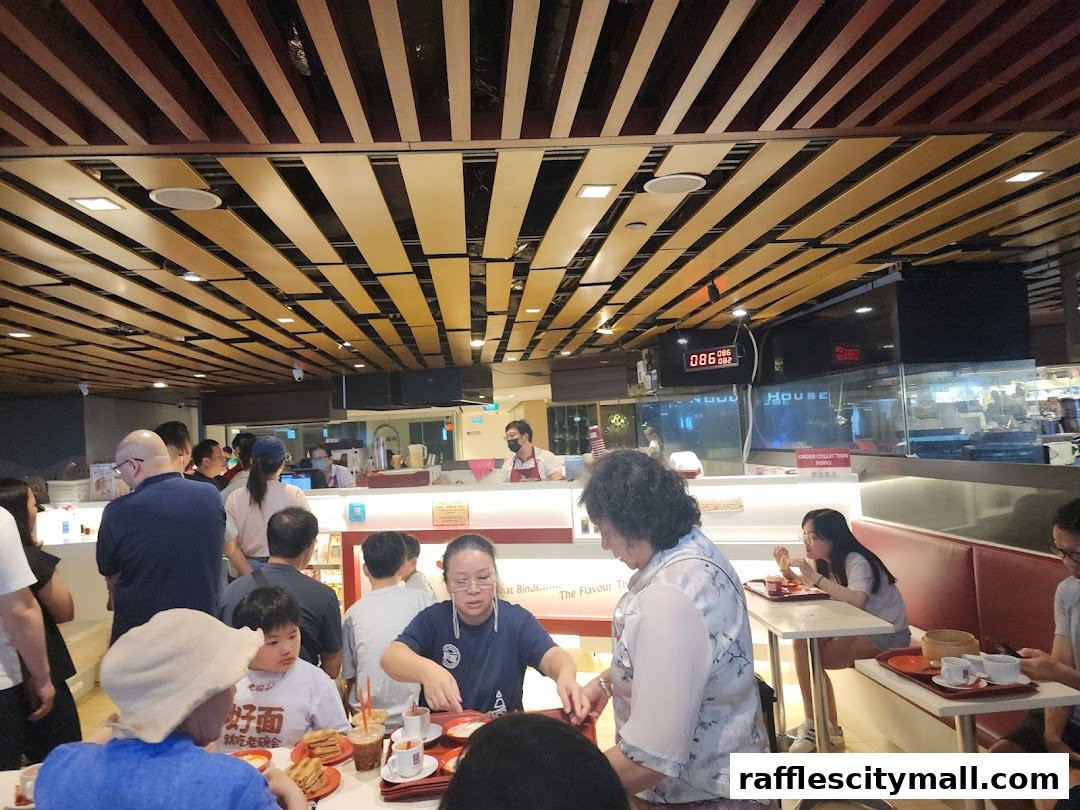 People dining at Ya Kun Kaya Toast, with a busy counter and modern ceiling.