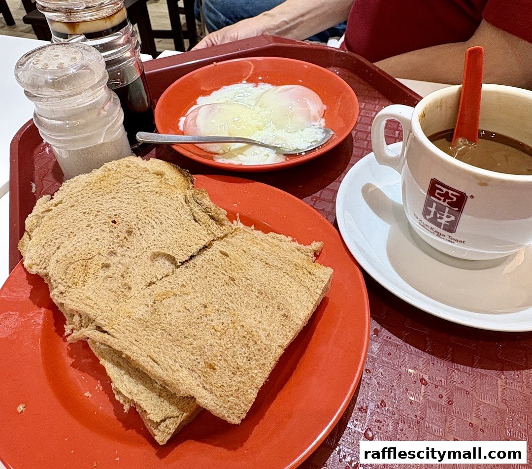 A tray of traditional Singaporean breakfast with kaya toast, soft-boiled eggs, and coffee.