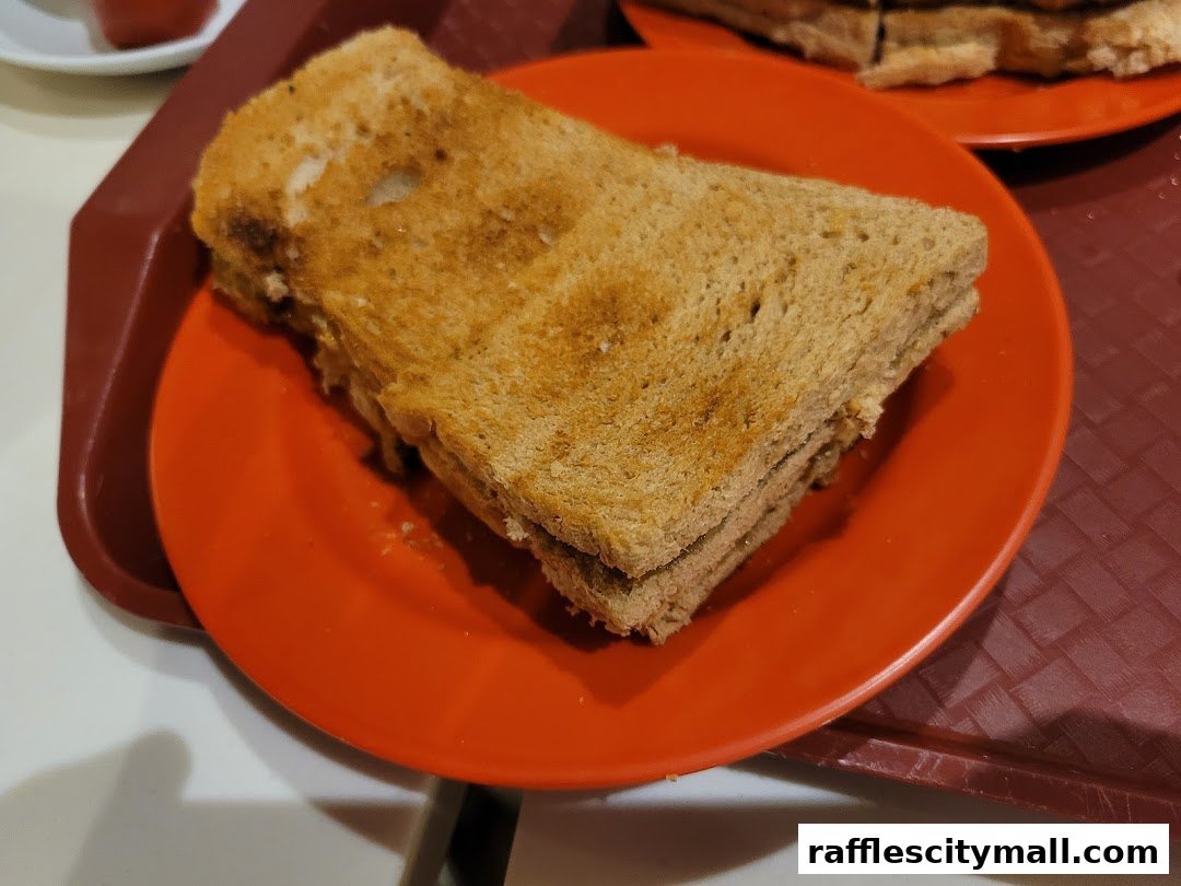 A close-up shot of kaya toast served on an orange plate, with another plate of toast in the background.