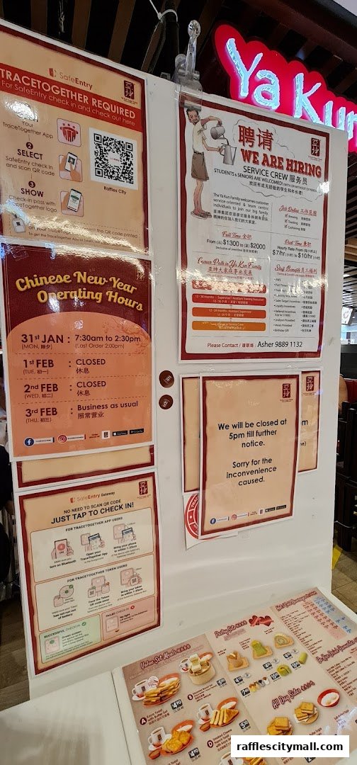 A display board with various notices including SafeEntry instructions, hiring information, and operating hours for Ya Kun Kaya Toast.