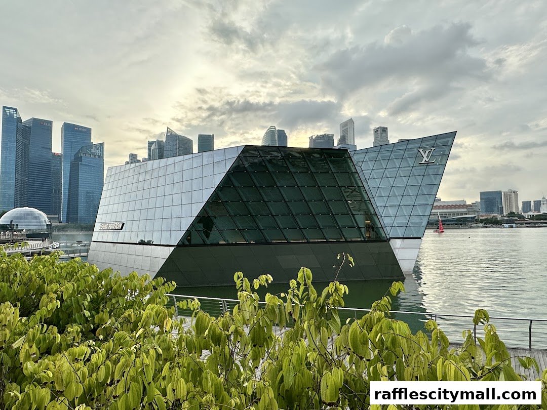 A striking modern building with glass facades, featuring the Louis Vuitton logo, situated by the water.