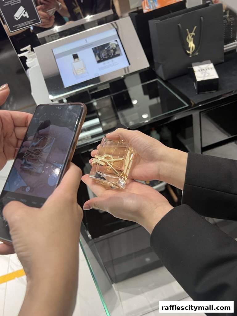 A person holds a YSL perfume bottle while another person photographs it with a smartphone.